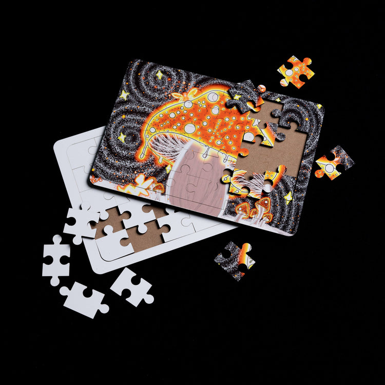 A partially completed jigsaw puzzle with orange and yellow celestial design, featuring planets and stars, scattered on a black background alongside loose puzzle pieces.