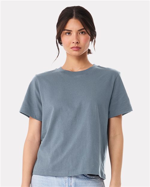 Load image into Gallery viewer, A person with long dark hair wears a plain BELLA + CANVAS Women's 6 oz Heavyweight Tee and light blue jeans, standing against a white background and looking straight at the camera, reflecting sustainable manufacturing.