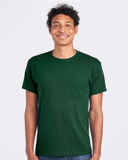 Load image into Gallery viewer, A person with curly hair smiles while wearing a dark green JERZEES Dri-Power® 50/50 Pocket T-Shirt, made through socially conscious manufacturing, against a plain white background.