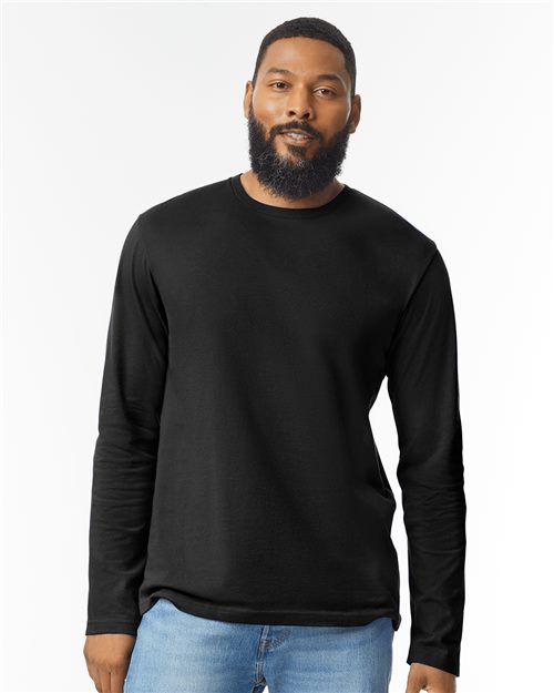Load image into Gallery viewer, A bearded person wearing a Gildan Softstyle® Long Sleeve T-Shirt and blue jeans stands against a plain white background.