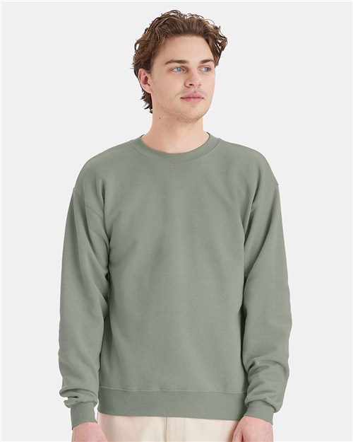 Load image into Gallery viewer, A person wearing a Hanes - Ecosmart® Crewneck Sweatshirt in light green gazes to the side against a white background. Their short, wavy hair frames their neutral expression, embodying the brand's commitment to sustainable manufacturing.