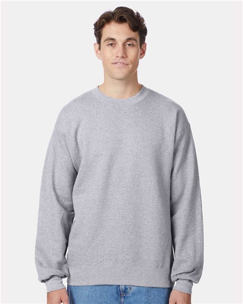 Load image into Gallery viewer, A person in a Hanes Ultimate Cotton® Crewneck Sweatshirt and blue jeans, both crafted through socially conscious manufacturing, stands against a plain white background.