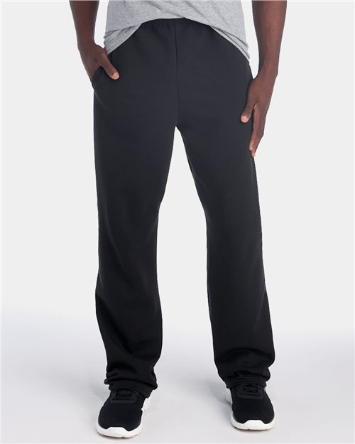 Load image into Gallery viewer, Someone proudly flaunts their sustainable style in JERZEES NuBlend® Open-Bottom Sweatpants with Pockets. Paired with a gray shirt and black sneakers featuring white soles, this ensemble is ideal against a plain background, offering both comfort and durability.