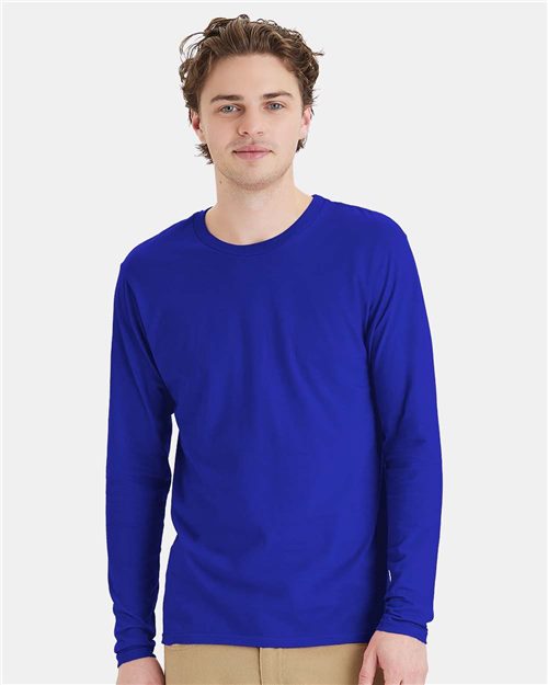 Load image into Gallery viewer, A person with short, wavy hair wears a Hanes Perfect-T Long Sleeve T-Shirt in bright blue, made from ring-spun cotton, and beige pants, standing against a plain white backdrop.