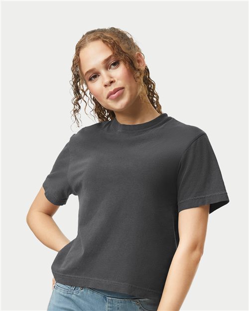 Load image into Gallery viewer, A curly-haired individual stands against a light background, wearing a Comfort Colors Women's Heavyweight Boxy T-Shirt and blue jeans. They smile gently with one hand on their hip, effortlessly showcasing the allure of sustainable clothing.