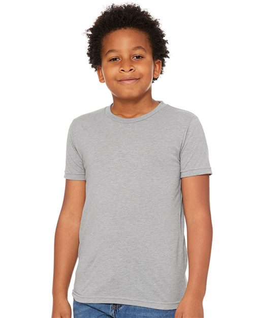 Load image into Gallery viewer, A curly-haired child smiles in a BELLA + CANVAS Youth Triblend Tee, made with Blue Sign certified dyes, and blue jeans, standing against a white backdrop.