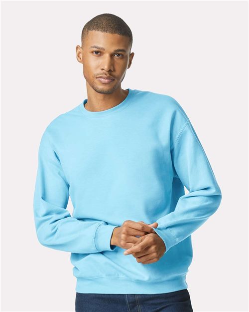 Load image into Gallery viewer, Wearing the Gildan Softstyle® Midweight Crewneck Sweatshirt in bright blue with dark jeans, a person stands against a white background, looking at the camera with hands loosely clasped, showcasing sustainable fashion.