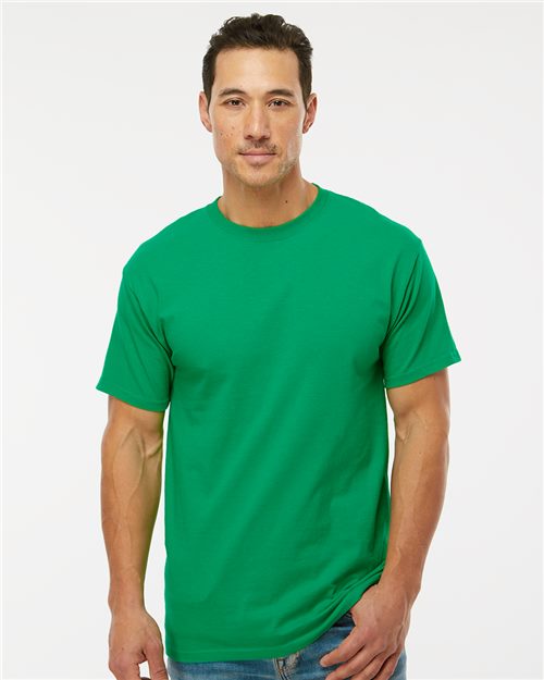Load image into Gallery viewer, A person with short dark hair is wearing an M&O - Gold Soft Touch T-Shirt in plain green, made of 100% cotton, paired with blue jeans. The preshrunk jersey tee pops against the white backdrop, emphasizing M&O's dedication to sustainable manufacturing.