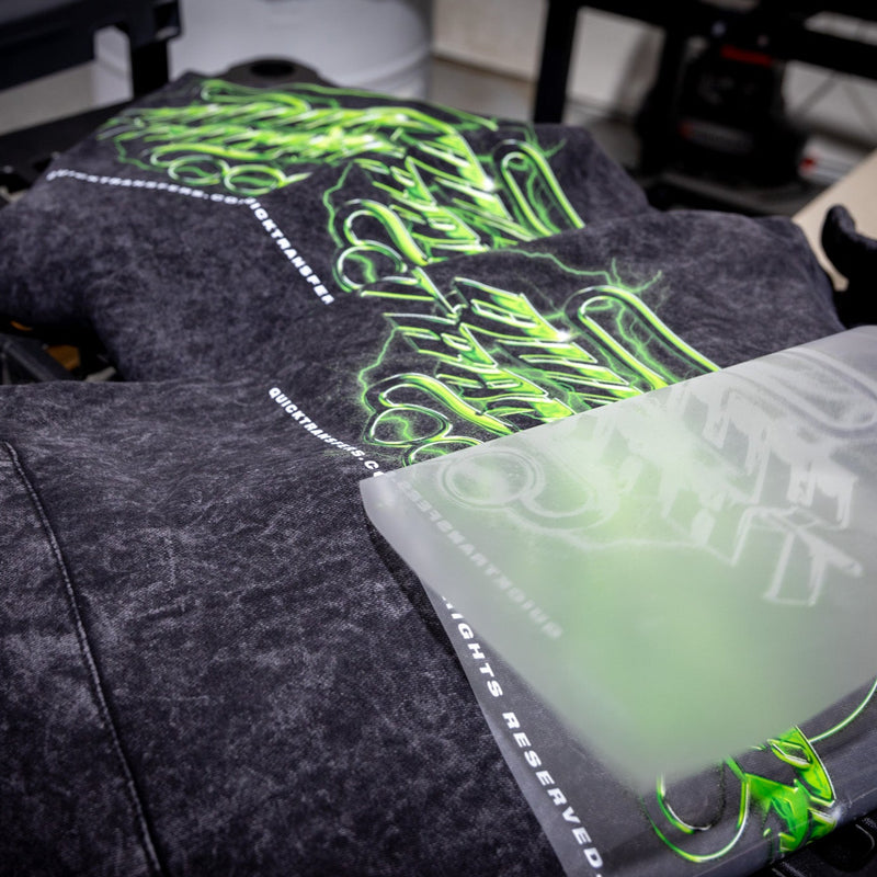 Load image into Gallery viewer, A black garment on a heat press features a neon green and white graphic design from Quick Transfers' FASTFILM™ DTF TRANSFERS, with "Cultural Atrocity" and "All Rights Reserved" prominently displayed in high-quality customized transfers near the shirt's edge.