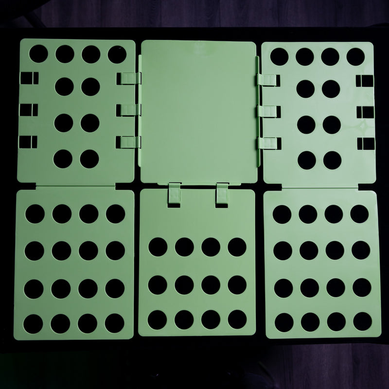 Load image into Gallery viewer, The Shirt Folder by Quick Transfers is a green plastic board with hinged sections and cut-out circles, perfect for perfectly folded shirts. It lays flat against a dark background, highlighting its innovative design for efficient shirt organization.
