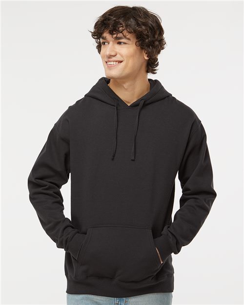 Load image into Gallery viewer, A person wearing a Hanes - Perfect Fleece Hooded Sweatshirt stands smiling with hands in the front pocket, paired with blue jeans against a plain light gray background.
