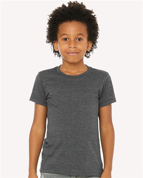 Load image into Gallery viewer, A curly-haired child stands against a plain backdrop, wearing the BELLA + CANVAS Youth CVC Jersey Tee in dark gray Airlume combed cotton and light pants. Facing the camera with a neutral expression, they highlight the unisex sizing of this sustainably made outfit from BELLA + CANVAS.
