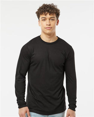 A young man with curly hair confidently poses against a white background, wearing a Tultex Poly-Rich Long Sleeve T-Shirt in black and light blue jeans.