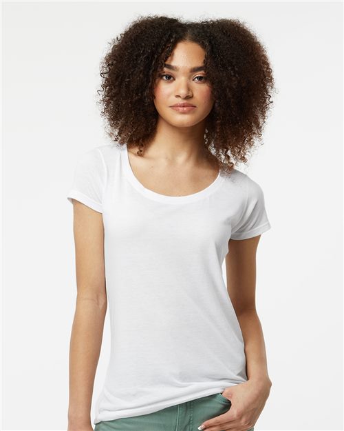 Load image into Gallery viewer, A curly-haired person wears a Tultex Women&#39;s Poly-Rich Scoop Neck T-Shirt and green pants against a plain white backdrop, with one hand in their pocket, gazing directly at the camera.
