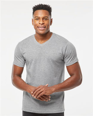 A person in a Tultex Poly-Rich V-Neck T-Shirt from the brand Tultex, made of USA cotton, stands smiling with hands clasped against a plain white background.