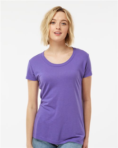 Load image into Gallery viewer, A person with short blonde hair wears a Tultex Women&#39;s Tri-Blend T-Shirt in purple, paired with jeans. They stand against a plain white background, smiling slightly while looking directly at the camera.
