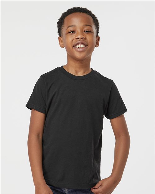 Load image into Gallery viewer, A child smiles against a plain background, wearing a Tultex - Youth Poly-Rich T-Shirt in black and dark blue jeans, with their arms relaxed by their sides.
