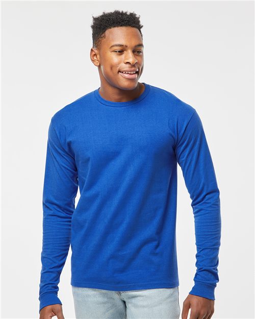 A man in a Tultex Heavyweight Jersey Long Sleeve T-Shirt, bright blue in color, and light blue jeans made of ring-spun cotton smiles against a plain white background.