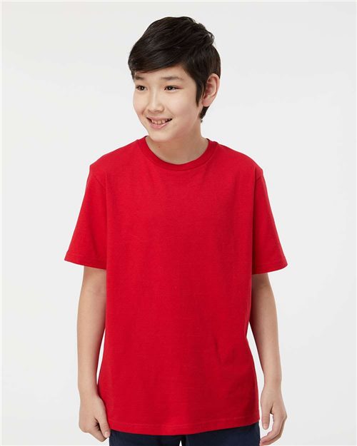 A young person with short dark hair smiles, wearing a Tultex - Youth Heavyweight Jersey T-Shirt. Crafted from ultra-soft, ring-spun cotton, the bright red tee stands out against a plain white background, showcasing its vibrant color and sustainable quality by Tultex.