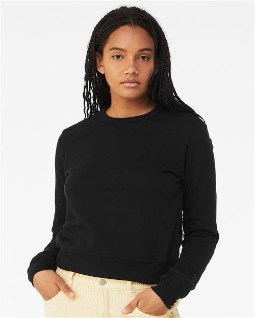 Load image into Gallery viewer, A person with long braided hair wears a BELLA + CANVAS Women&#39;s Sponge Fleece Classic Crewneck Sweatshirt in black, paired with light-colored pants. They stand against a plain white background, hands in pockets, looking at the camera.
