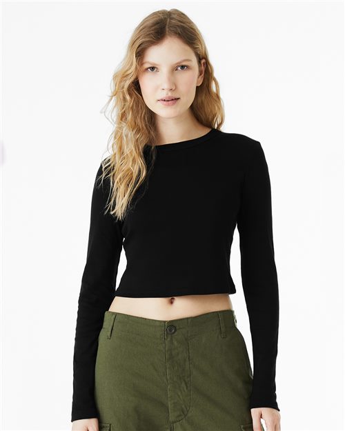 Load image into Gallery viewer, A person with long, wavy hair is wearing a BELLA + CANVAS Women&#39;s Micro Rib Long Sleeve Baby Tee in black and green pants. They face forward against a plain white background, highlighting the brand&#39;s sustainable manufacturing and Airlume combed fabric commitment.
