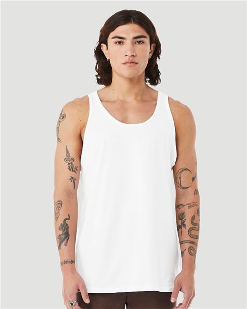 A person with long hair and tattooed arms wears a BELLA + CANVAS - Heather CVC Tank, made from Airlume combed cotton. They stand against a light gray background, looking directly at the camera, embodying style and eco-friendly sophistication.