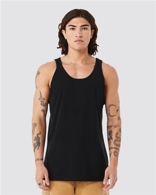 A person with shoulder-length hair wears a black BELLA + CANVAS - Triblend Tank and beige pants, standing against a plain gray background. Tattoos of animals and shapes adorn their arms, perfectly highlighted by the tank's retail fit. They gaze directly into the camera.