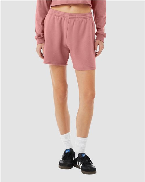 Load image into Gallery viewer, A person wears a pink long-sleeve top with BELLA + CANVAS Women&#39;s Cutoff Fleece Shorts in soft Airlume combed cotton, paired with white crew socks and black sneakers with white stripes, all set against a plain gray backdrop.
