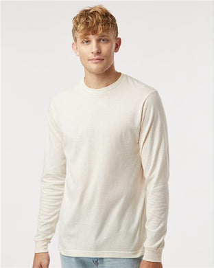 A young man with curly blonde hair in a Tultex Fine Jersey Long Sleeve T-Shirt and ring-spun cotton jeans stands against a minimalist white background.