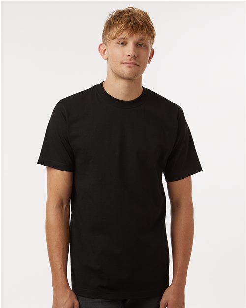 A person with short tousled hair wears a Tultex Heavyweight Street T-Shirt, made from USA cotton, reactive-dyed for lasting color, against a white background. They look directly at the viewer.