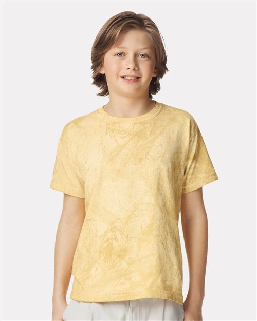 A smiling person with medium-length hair wears a Comfort Colors - Colorblast™ Youth Heavyweight T-Shirt in light yellow, made from garment-dyed cotton. It offers a relaxed fit and sustainable style, standing out against a plain background while being OEKO-TEX certified.