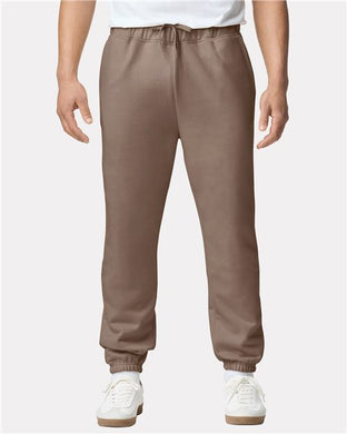 A person in Gildan - Softstyle® Midweight Pocket Sweatpants made from an OEKO-TEX certified cotton/polyester blend, featuring an elastic waistband and drawstring, paired with a white t-shirt and white sneakers against a plain white background.