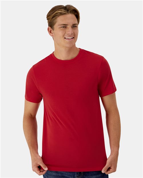 Load image into Gallery viewer, A person with short brown hair smiles in a Hanes - Cool DRI® Cotton Touch T-Shirt, crafted from ring-spun polyester jersey for moisture management. They stand against a light gray background, hands casually by their sides.
