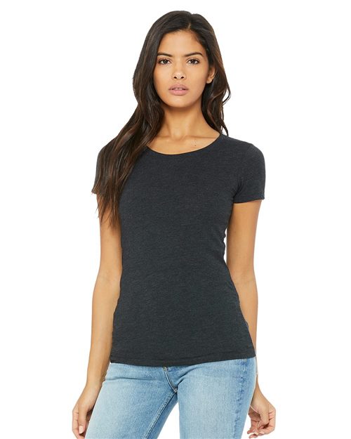 Wearing a dark gray BELLA + CANVAS Women's Triblend Tee made with Blue Sign certified dyes and semi-relaxed light blue jeans, a person with long dark hair stands against a white background, one hand by their side and a neutral expression on their face.