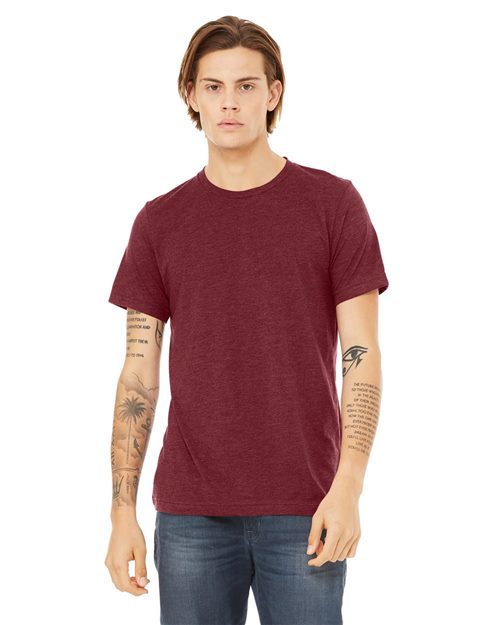 Load image into Gallery viewer, A person with medium-length hair tattoos on both arms stands against a white background, wearing a BELLA + CANVAS Triblend Tee in maroon and jeans, highlighting sustainable manufacturing and comfort.
