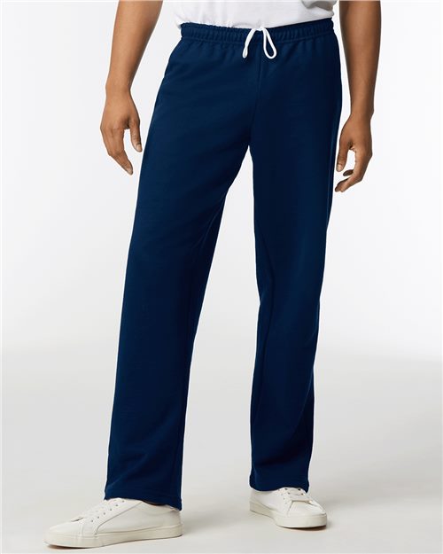 Load image into Gallery viewer, Someone is wearing Gildan - Heavy Blend™ open-bottom lounge pants in dark blue, crafted from OEKO-TEX certified fabric, featuring a drawstring waist, paired with white sneakers against a plain white background.
