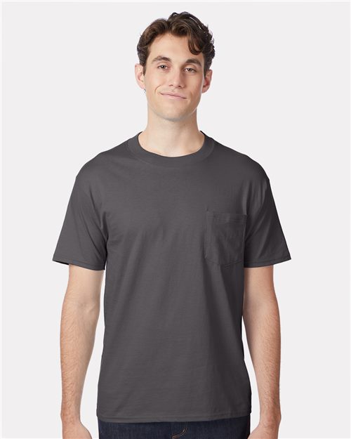 Load image into Gallery viewer, A person in a dark gray Hanes Beefy-T® Pocket T-Shirt, made from ring-spun cotton, stands against a white background, smiling with short, wavy hair and wearing dark pants.
