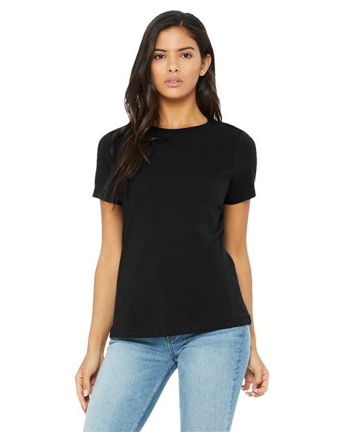 A person with long hair stands against a white background wearing a plain black BELLA + CANVAS Women’s Relaxed Jersey Tee and light blue jeans. Made from Airlume combed cotton via sustainable methods, the shirt drapes gently as their hands rest by their sides.