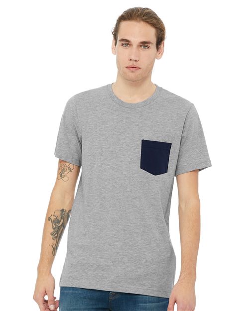 Load image into Gallery viewer, A person with long hair stands against a white background, wearing a BELLA + CANVAS - Jersey Pocket Tee in gray made from Airlume combed and ring-spun cotton. The tee features a dark pocket that complements their tattooed left arm and jeans.
