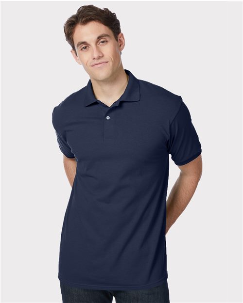 Load image into Gallery viewer, A man wearing a Hanes - Ecosmart® Jersey Polo in navy stands against a white backdrop. With short dark hair and a subtle smile, he represents socially conscious manufacturing, promoting fairness and sustainability with hands behind his back.
