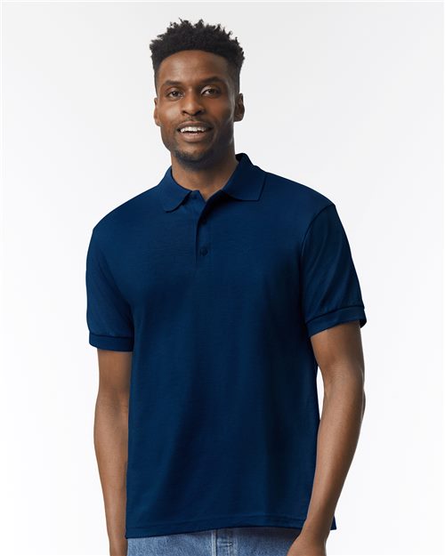 Load image into Gallery viewer, A person smiles while wearing a Gildan DryBlend® Jersey Polo in navy blue, made from moisture-wicking fabric, standing against a plain white background with light blue jeans.
