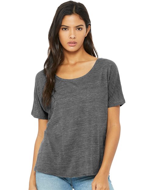 Load image into Gallery viewer, A person with long dark hair wears a BELLA + CANVAS Women’s Slouchy Tee in gray and light blue jeans against a white background. Their neutral expression reflects the brand&#39;s commitment to sustainable manufacturing.
