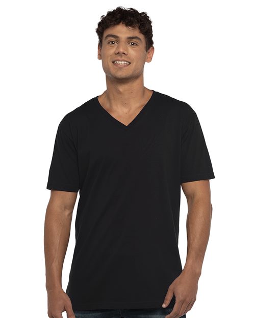 A person in a Next Level Cotton V-Neck T-Shirt and jeans stands against a white background, looking straight ahead with a slight smile and relaxed posture.