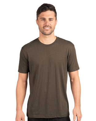 Wearing a Next Level - Triblend T-Shirt, a person with short dark hair smiles against a plain white background, embodying effortless sustainable style.