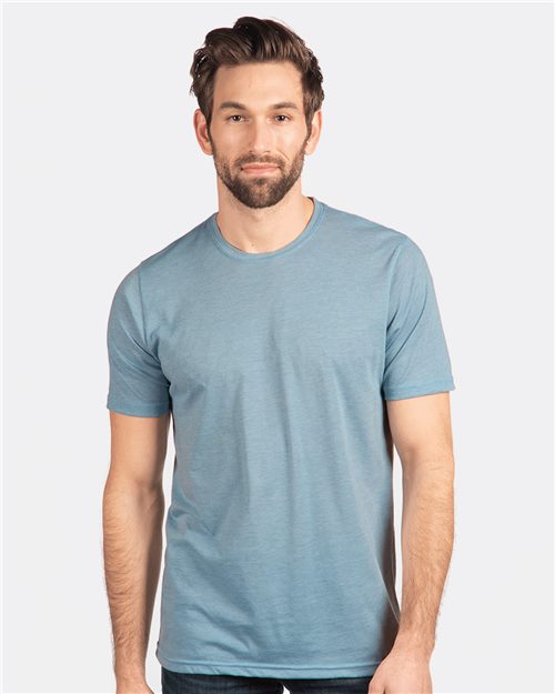 A man with short brown hair and a beard wears a light blue Next Level Festival T-Shirt, crafted from breathable polyester/cotton blend. He stands against a plain white backdrop, looking directly at the camera with a neutral expression.