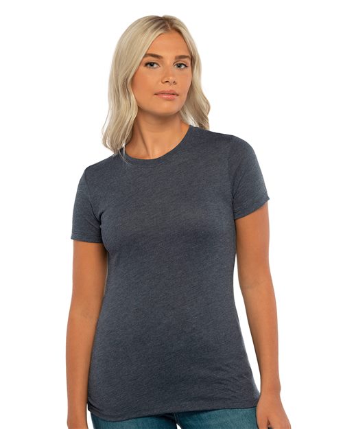 A person with long, light-colored hair wearing a fitted dark gray Women's Triblend T-Shirt by Next Level and blue jeans stands against a plain white background.