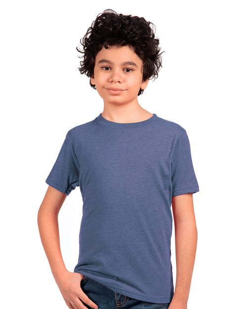 A curly-haired child wears a Next Level Youth Triblend T-Shirt in blue and jeans, with one hand in a pocket, standing against a white background.