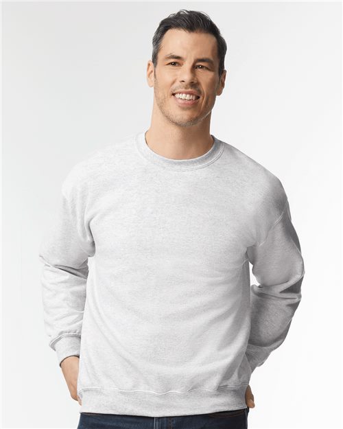 Load image into Gallery viewer, A person smiles in a Gildan - DryBlend® Crewneck Sweatshirt, light gray from the OEKO-TEX certified collection, and dark pants, hands in pockets before a plain white background.
