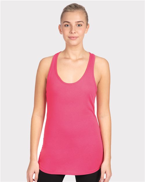 Load image into Gallery viewer, A person in a bright pink Next Level Women&#39;s Ideal Racerback Tank, made of a cotton/polyester blend, and black leggings poses against a white background, hair tied back with a neutral expression, showcasing sustainable style.
