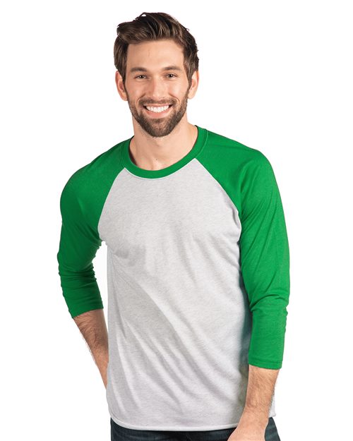 A smiling, bearded man models the sustainable Next Level Triblend Three-Quarter Raglan T-Shirt, featuring gray and green baseball-style design with green 3/4-length sleeves and collar, against a white background. His short brown hair complements the look.